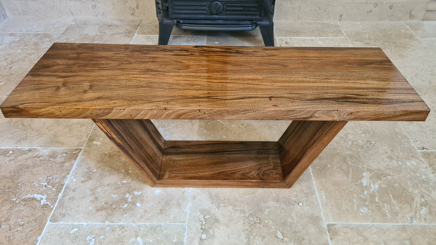 Vue latérale de la table en noyer mettant en valeur le veinage et les pieds inclinés