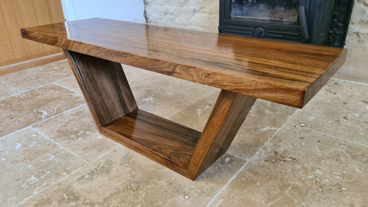 Table basse artisanale en noyer massif avec bord naturel et pieds inclinés
